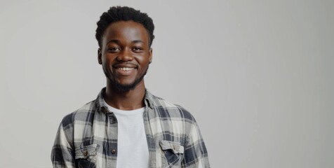 Obraz premium Smiling Young Man with a Checkered Shirt Posing Against Gray Background in Studio