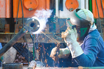 Welder is welding metal flange to connect with steel pipe for using as improvement material in oil...