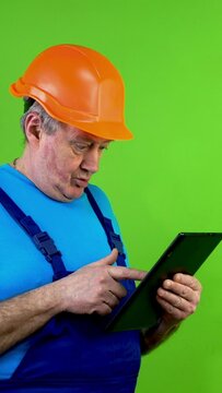Senior repairman in overalls sees something on tablet, not understand anything.