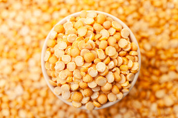 Uncooked, split, yellow peas in bowl. Dry peas grains. Top view