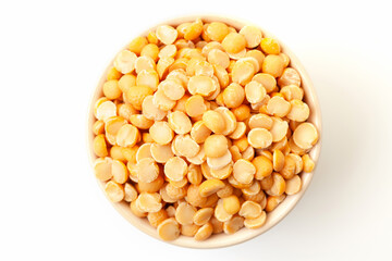Uncooked, yellow peas in bowl on white background. Top view