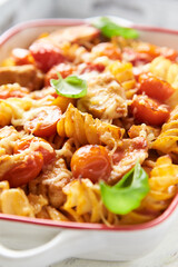 Pasta with chicken breast, cherry tomatoes and fresh basil. Bright wooden background. Close up.
