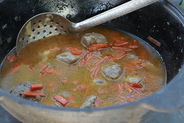 Georgian dish khortsione. Prepared in a cauldron. Vegetables and meat in sauce. Food cooked over a fire. Close-up. Selective focus. Place for an inscription.