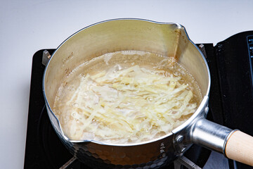 短冊切りのジャガイモを鍋で茹でる