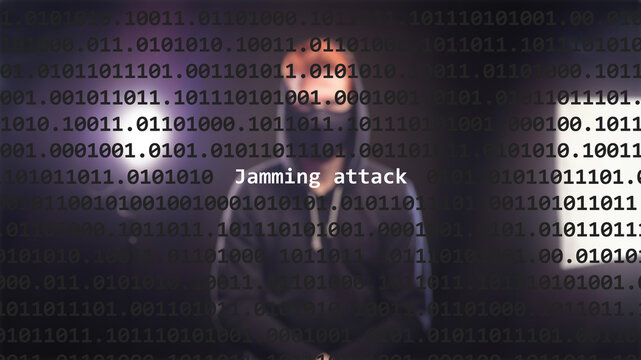 Cyber attack jamming attack text in foreground screen, anonymous hacker hidden with hoodie in the blurred background. Vulnerability text in binary system code on editor program.