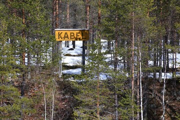 Wooden sign in the forest with the Swedish word Kabel (cable) written on it