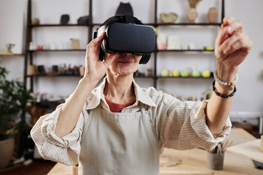 Portrait of mature woman using VR visualizing art project in workshop, copy space - Powered by Adobe