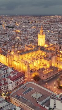Seville cathedral at night, flying around the famous gothic Cathedral in Seville, Andalusia region, Spain. Aerial view of Seville Cathedral and Giralda bell tower. Andalusian capital drone footage