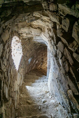 Steep stone staircase in the wall of the tower. Arched window, stone walls, loopholes