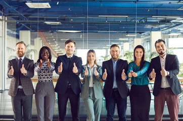 Group of multinational diverse business people showing thumbs up with wide smile in an office...