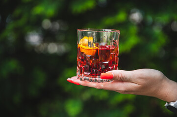 A refreshing iced beverage held by a hand against a vibrant green background.