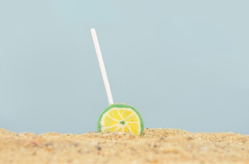 Yellow and green lollypop dropped into the sand on beach in summer. 