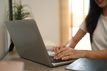 Hand of young female typing on laptop keyboard, working online or searching information