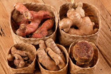 rempah-rempah. ginger, galangal, kencur, turmeric, secang wood, and palm sugar. Javanese herbal medicine. served in a woven bamboo container on a wooden table.  spices and herbs. 
