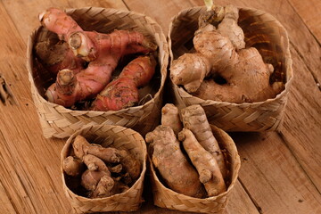rempah-rempah. ginger, galangal, kencur, turmeric, secang wood. Javanese herbal medicine. served in a woven bamboo container on a wooden table. spices and herbs.