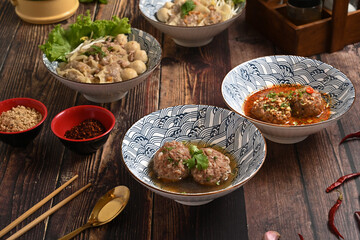 Tasty scalded meatballs and dumplings soups on rustic wooden background