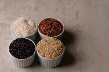 various rice in a white ceramic bowl. There are brown rice, black rice, brown and white. Rice is the staple food of most Asians. Oryza sativa. beras merah, beras hitam, beras coklat.