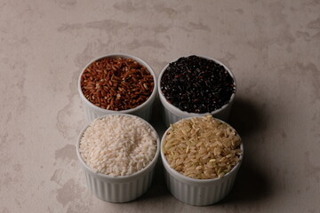various rice in a white ceramic bowl. There are brown rice, black rice, brown and white. Rice is the staple food of most Asians. Oryza sativa. beras merah, beras hitam, beras coklat. 