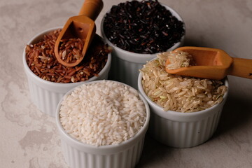 various rice in a white ceramic bowl. There are brown rice, black rice, brown and white. Rice is the staple food of most Asians. Oryza sativa. beras merah, beras hitam, beras coklat. 