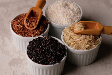 various rice in a white ceramic bowl. There are brown rice, black rice, brown and white. Rice is the staple food of most Asians. Oryza sativa. beras merah, beras hitam, beras coklat.