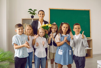 Students make a little surprise for their teacher. Group portrait of happy children and a woman...