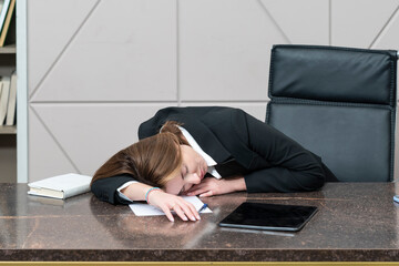 Tired frustrated and overworked business woman sleeping on the desktop in the office