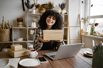 Small business owner packing her handmade product into cardboard box. E-commerce entrepreneurship....