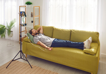 Side view of smiling man lying with closed eyes on the couch at home or in medical clinic while...