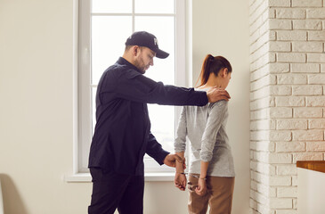 Policeman is arresting a woman, putting handcuffs on her. The arrest is part of law enforcement...