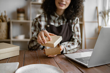 Entrepreneur sells dishes, plates and cups made of clay, ceramics online and packs them in boxes...