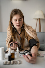 sick woman measures her blood pressure, she has stethoscope in her hands. High heart rate.