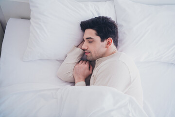 Photo of sleepy attractive man sleeping weekend day lying in soft bed white room interior inside