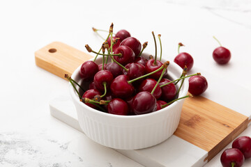 Ripe delicious cherries or sweet cherries in a white plate on a white background. Top view.