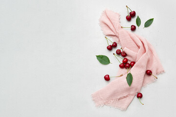 Ripe delicious cherries on a pink napkin on a light gray background. Top view. Space for text.
