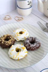 Detail shot of a gray plate with homemade donuts. Cream with orange and chocolate.