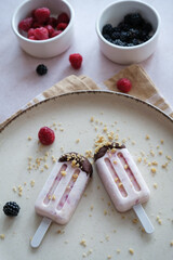 Raspberry ice cream on a plate with crushed nuts on top