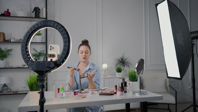 Beauty blogger woman filming review on cosmetic brushes in home studio, stream. Influencer of beauty industry demonstrating new brushes for makeup, native advertisement for followers in social media