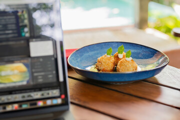 Food on a plate with laptop on wooden table.