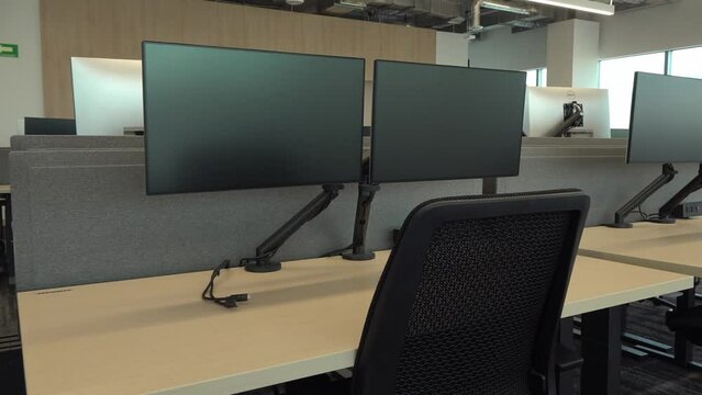 Room with workstations equipped with modern technological equipment installed on long wooden desks. Mexico.