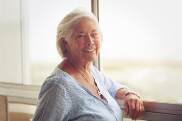 Portrait, senior woman and relax by window of retirement home for peace, memories or nostalgia with...