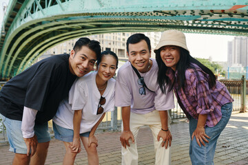 Friends posing under a bridge and smiling, enjoying a day out