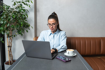 Young tired overworked business woman sitting in a coffee shop with laptop, taking a break from...