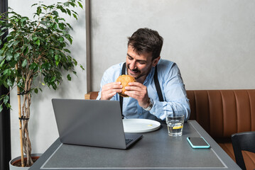 One young businessman small company owner, small business foreperson taking a lunch break eating...