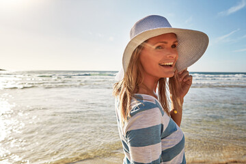 Woman, hat and happy at beach for holiday, fun and break as tourist in Miami. Female person, coast...