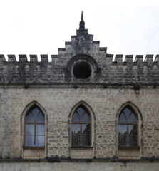 Beautiful details of old windows on rock wall. Facade of a medieval castle in Zugdidi, Georgia. Dadiani palace. vintage stone wall with arched window frames, reminiscent of medieval architecture.