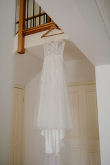 Elegant wedding gown hanging in front of a staircase at a home bridal event