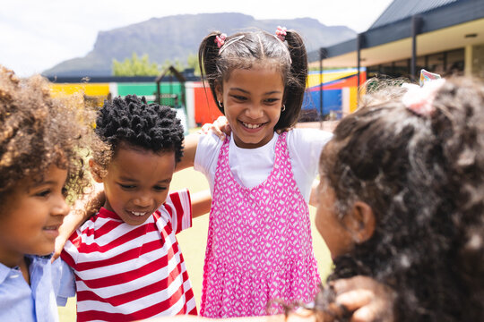 In school, diverse children are huddling together outside, smiling