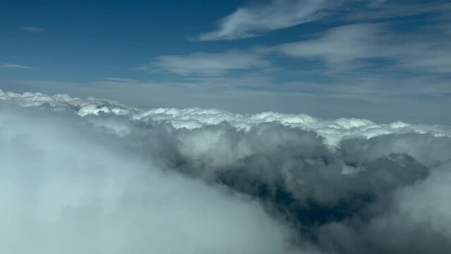 POV cloudscape shot from an airplane cockpit in a left turn over some flufly clouds. Immersive pilot view. Late afternoon light. 4K 60FPS.