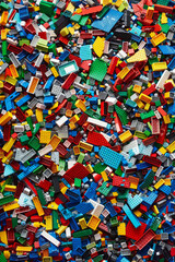 A chaotic yet colorful jumble of toy bricks, tightly packed to fill the entire frame. The bricks come in various sizes and an array of colors including red, blue, green, yellow, and white,