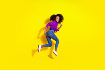 Full body photo of attractive young woman hurry running back dressed stylish violet clothes isolated on yellow color background